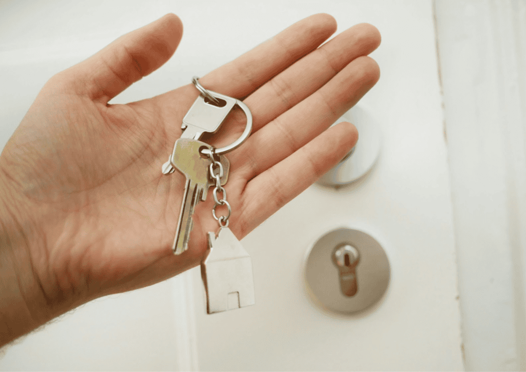 A close up picture of an open hand holding a set of keys in front of a lock on a door