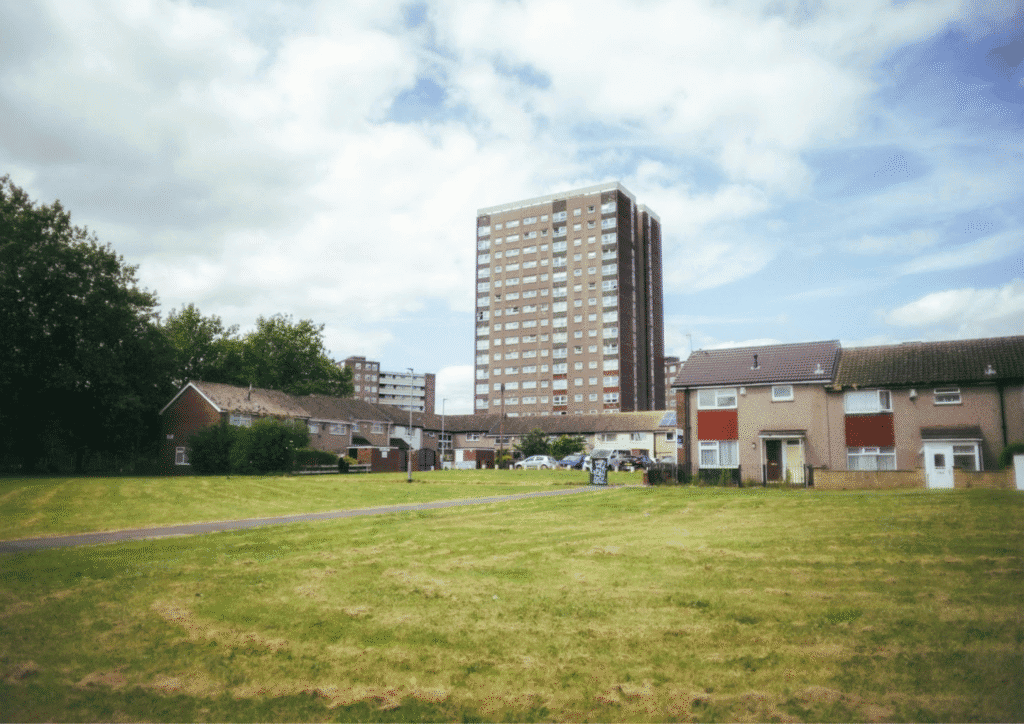 View from a field of a council estate, including some houses and a taller block of flats