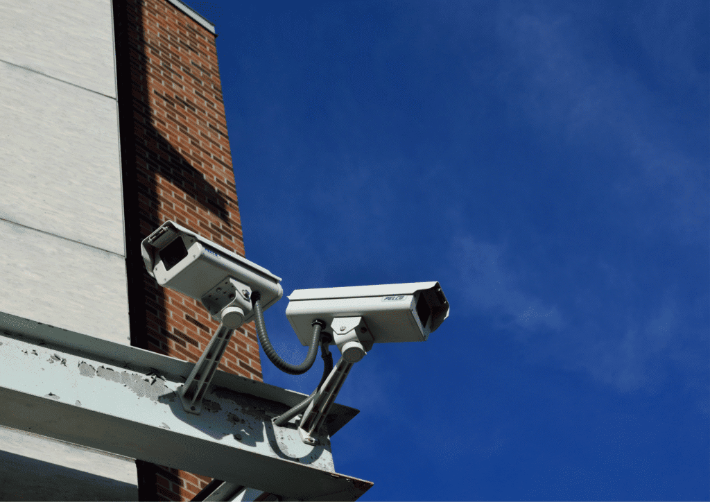 Two security cameras looking out from a brick building.